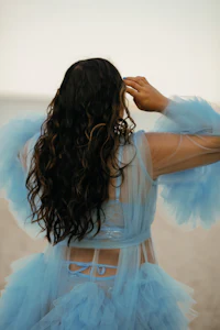 a woman wearing a blue tulle dress on the beach