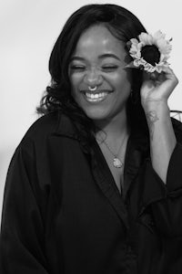 a black and white photo of a smiling woman holding a sunflower