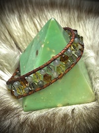 a bracelet with green and brown beads on top of a pyramid
