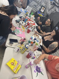 a group of people sitting around a table doing tattoos