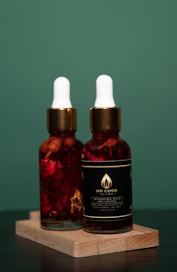 two bottles of rose oil on a wooden board
