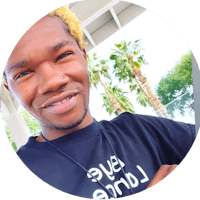 a young man with blond hair smiling in front of palm trees