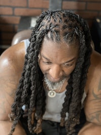 a man with long dreadlocks sitting at a barber shop