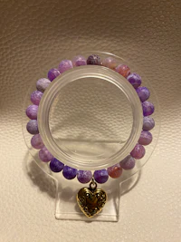 a purple and gold bracelet with a heart shaped bead