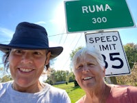 two women standing in front of a speed limit sign