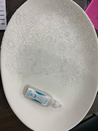 a plate with white flowers on it and a bottle of glue