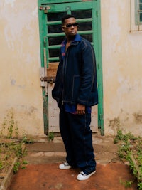 a man in a blue jacket standing in front of a door