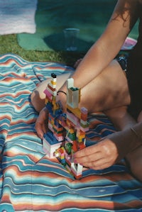 a woman playing with legos on a blanket