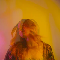 a woman with long hair in front of a yellow wall