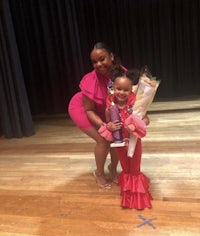 a young girl in a red dress poses for a picture with her mother