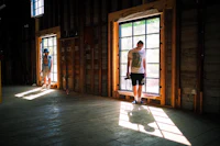 two people standing in a room with windows