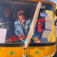 two people sitting in the back of a yellow rickshaw