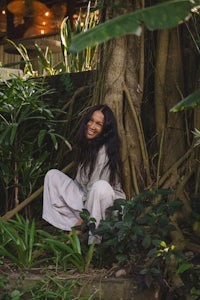 a woman sitting under a tree in a garden