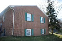 a brick building with green shutters