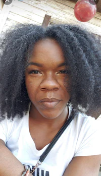 a woman wearing a white t - shirt with an afro