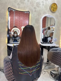 a woman with long hair sitting in a chair in a salon