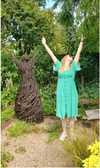 a woman in a green dress with her arms raised in the air