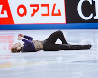 a male figure skater laying on the ice