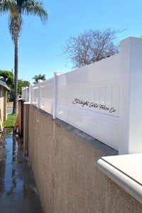 a white fence next to a palm tree