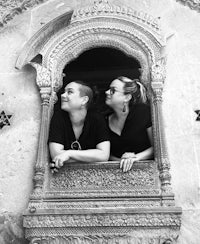 a black and white photo of two people looking out of a window