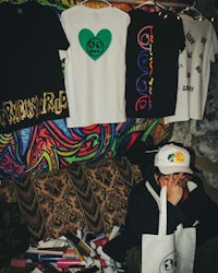 a man sitting on a couch with t - shirts and a bag