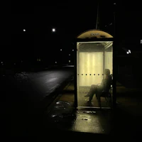a man sitting in a phone booth at night