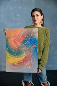 a woman holding up a colorful abstract painting