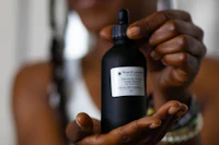 a woman holding up a bottle of black oil