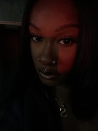 a black woman with piercings and a red light behind her