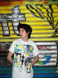 a young man holding a book in front of a graffiti wall