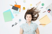 a young woman surrounded by a variety of office supplies
