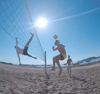 a group of people playing volleyball on the beach