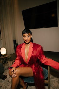 a woman in a red fur coat sitting on a chair