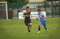 two young men playing soccer on a field