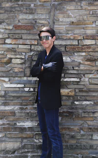 a man leaning against a stone wall