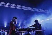 two djs on stage at an event with smoke in the background