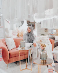 a woman in a hijab sitting on a pink couch