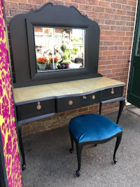 a black dressing table with a blue stool and mirror