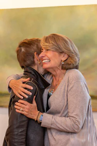 two women hugging in front of a painting