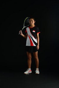 a woman holding a badminton racket on a black background