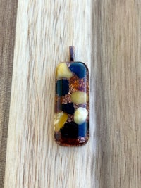 a black, brown and yellow glass pendant on a wooden table