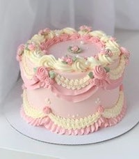 a pink cake decorated with white frosting and pink roses