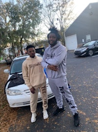 two men standing next to a car in a parking lot
