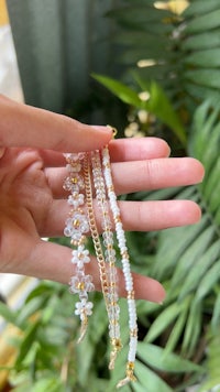 a hand holding a pair of white beaded bracelets
