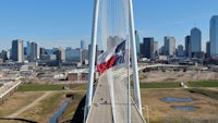 a texas flag is flying over a bridge in dallas
