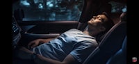 a man is sleeping in the back seat of a car