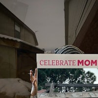 a woman is holding up a box that says celebrate mom