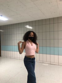 a girl standing in a hallway with a mask on her face