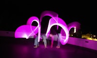 a group of people standing in front of a pink light sculpture