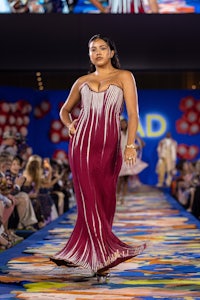 a model walks down the runway in a red dress